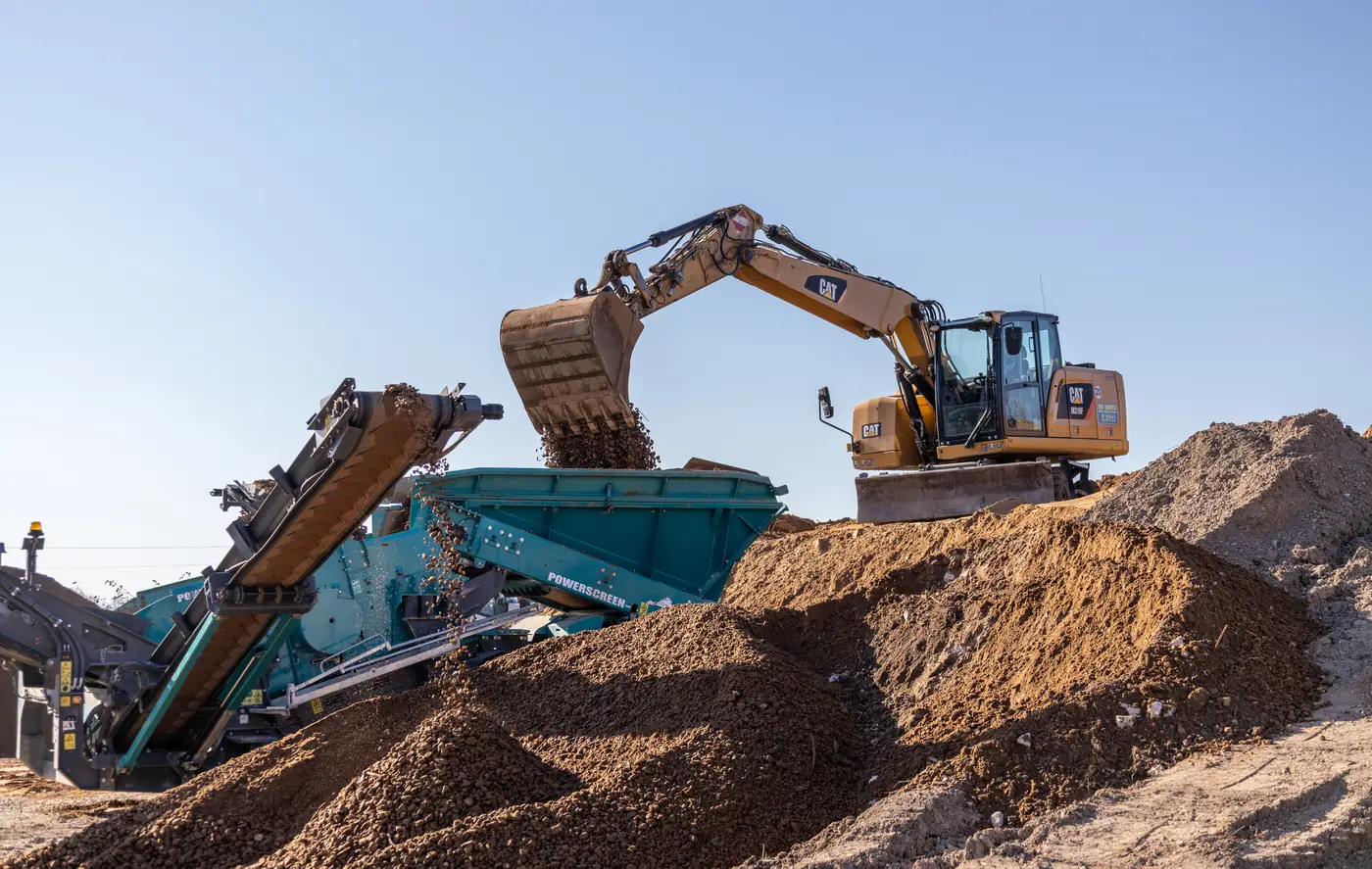 Bagger beschickt eine mobile Brecheranlage am Lagerplatz